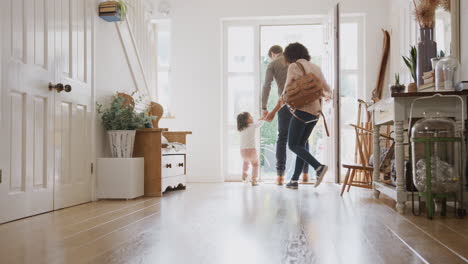 rear view of family leaving home on trip out with excited children