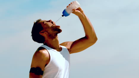 Sportler-Rehydriert-Mit-Wasser-Am-Strand