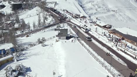 aerial view dolly in establishing of the mountain village of farellones completely snowed in, old man shoveling a mountain of snow, chile