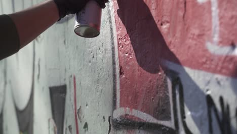 close up shot of a hand wearing black gloves painting graffiti on wall