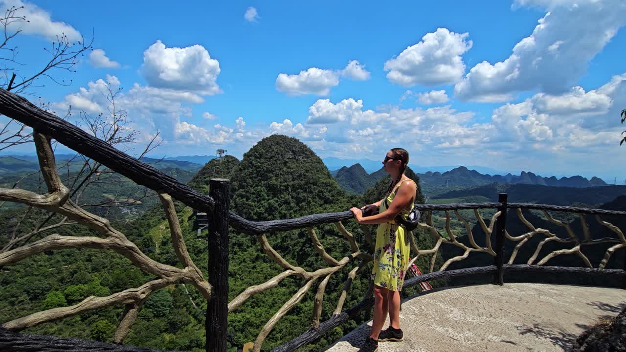 Female standing at a fence enjoying the view from Ruyi Peak, summer in Yangshuo