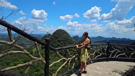 female standing at a fence enjoying the view from ruyi peak, summer in yangshuo