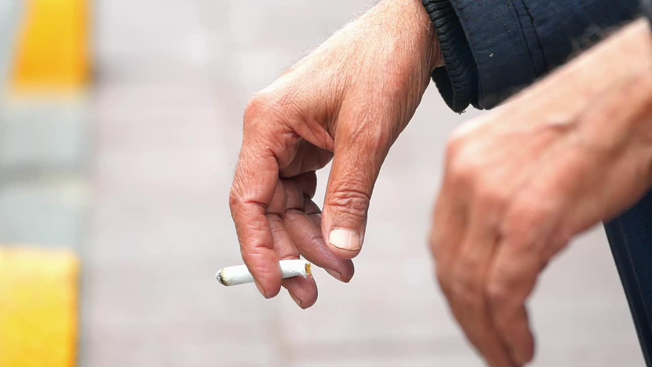Close-up of a Smoker's Hand Holding a Lit Cigarette