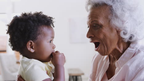 abuela sentada en el sofá en casa con la nieta bebé jugando juntos