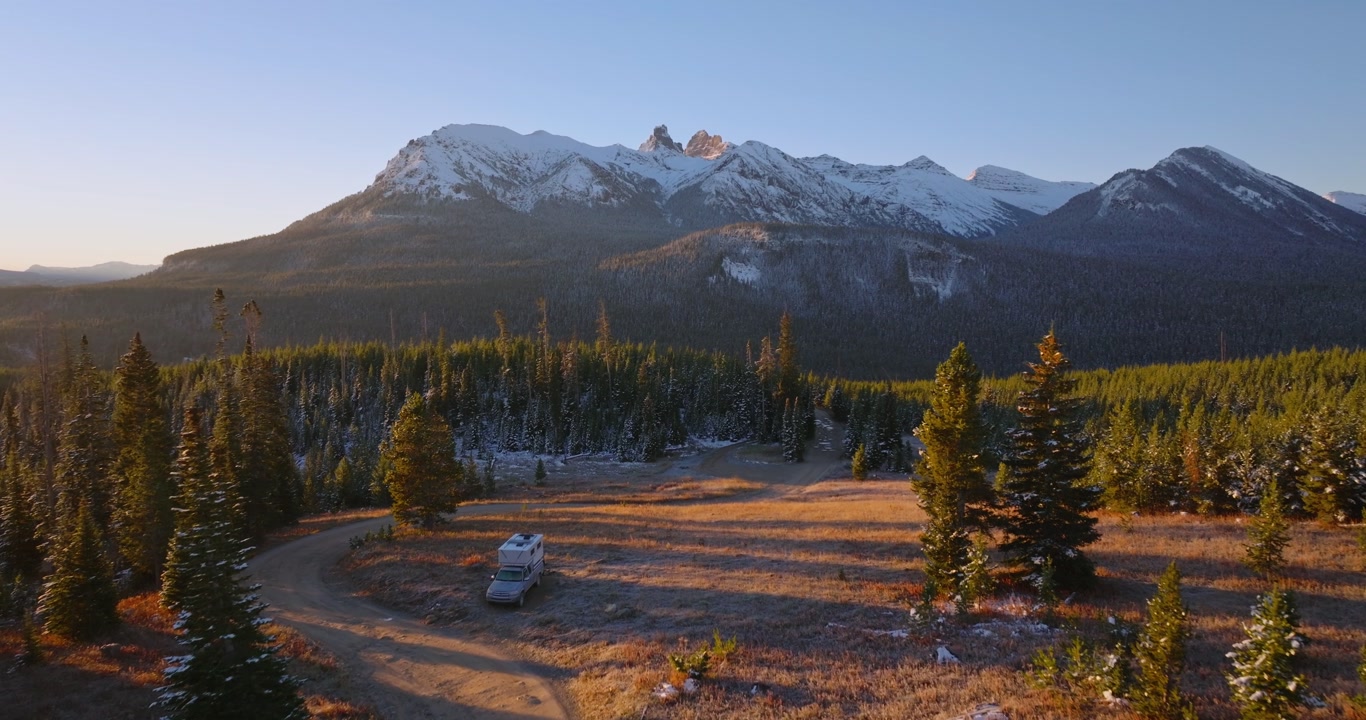 Mountain range rising above evergreen forest near Cooke City Montana at sunrise, solo camper travels and stops for the night