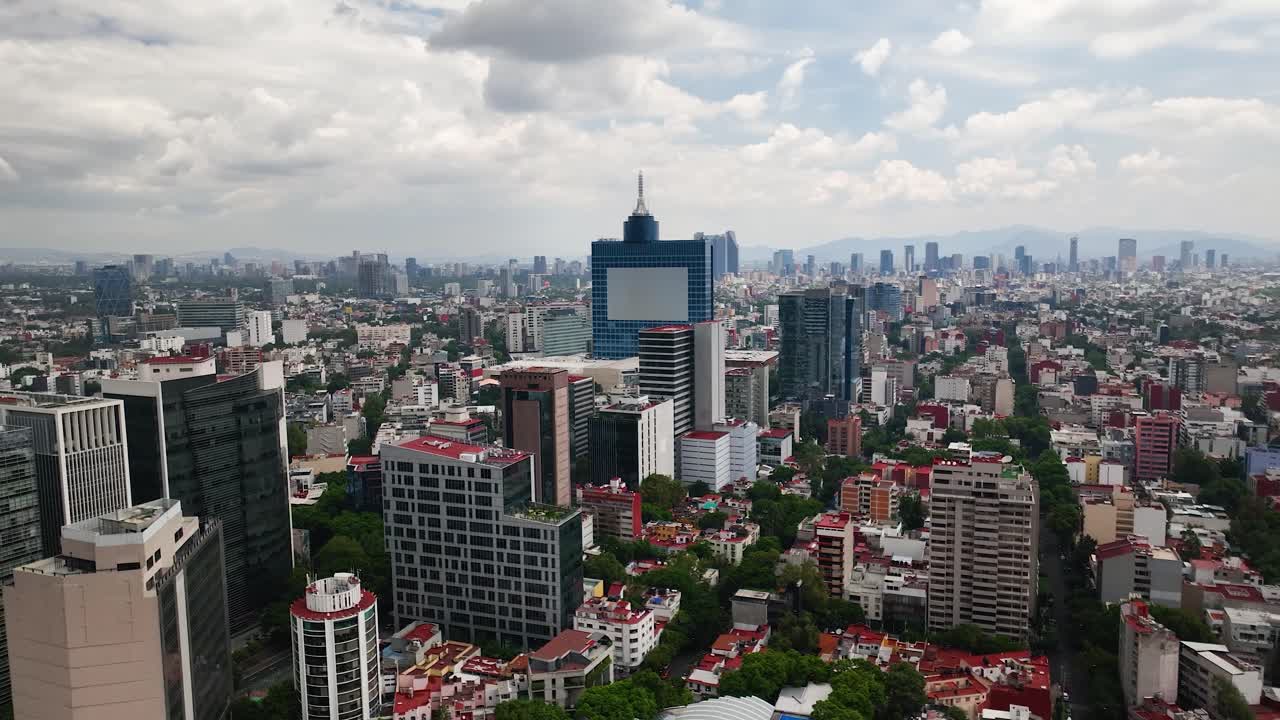 Drone traveling shot above Colonia del Valle in Mexico City. World Trade Center stands out amid dense skyline, leafy streets, famous avenues, small parks under cloudy daylight—clean, cinematic