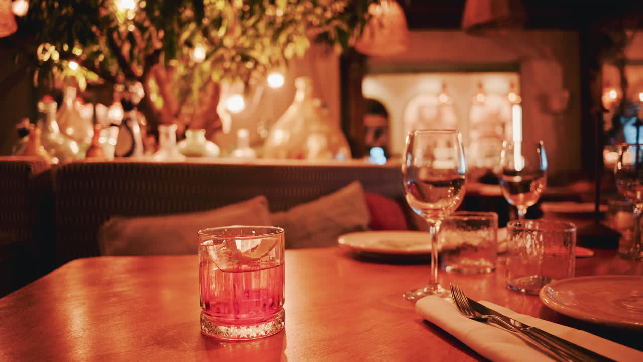 Close up of a cocktail served on a wooden table in a warmly lit restaurant