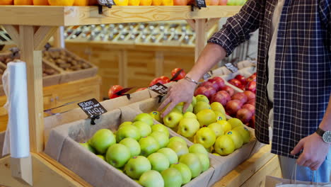 man shopping for apples at a grocery store