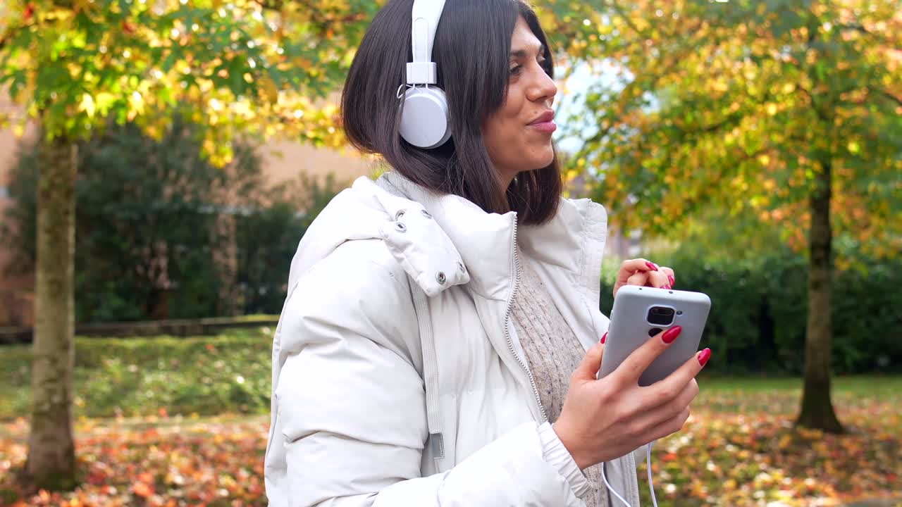 Woman with Headphones Listening to Music in Autumn