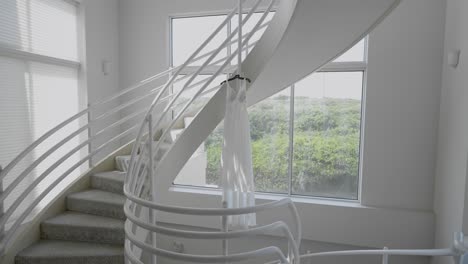 bride's wedding dress elegantly hanging in the stairwell