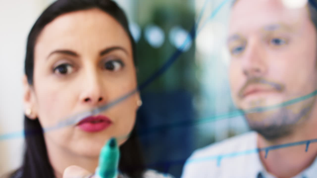 ingeniera dibujando un gráfico en vidrio que muestra la fórmula matemática de un estudiante en una conferencia universitaria creativa enseñando ideas compartiendo datos en un laboratorio de vidrio moderno