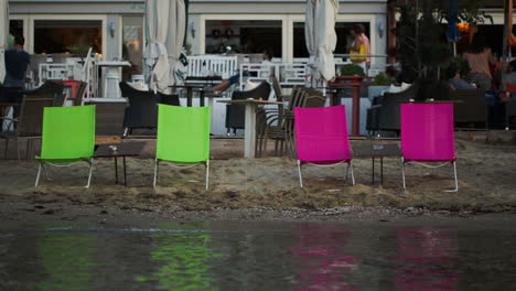 Four-empty-chaise-lounges-on-the-beach-with-cafe-behind