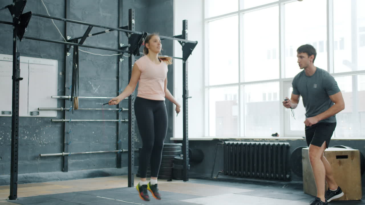 Woman Jumping Rope with Personal Trainer in Gym