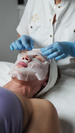A Masseuse Placing a Facial Mask on the Client's Face in a Spa - Close Up
