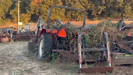 broken tractor and rusting machinery with growing weeds in a dirt patch in oregon