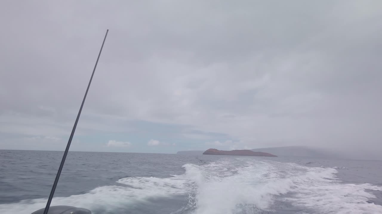 Gimbal POV shot looking out the back of a moving boat with Molokini Crater in the distance on the island of Maui, Hawai'i