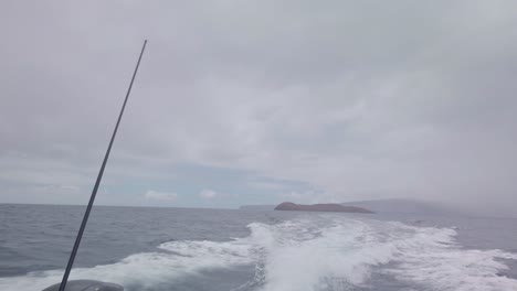 gimbal pov shot looking out the back of a moving boat with molokini crater in the distance on the island of maui, hawai'i