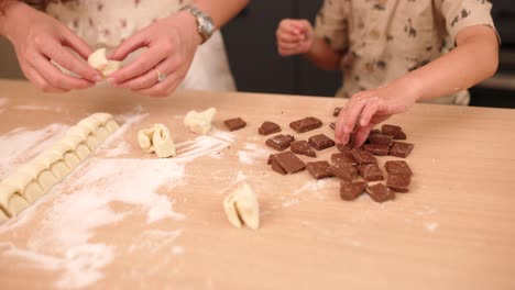 Crop mother and son preparing roll with chocolate at home