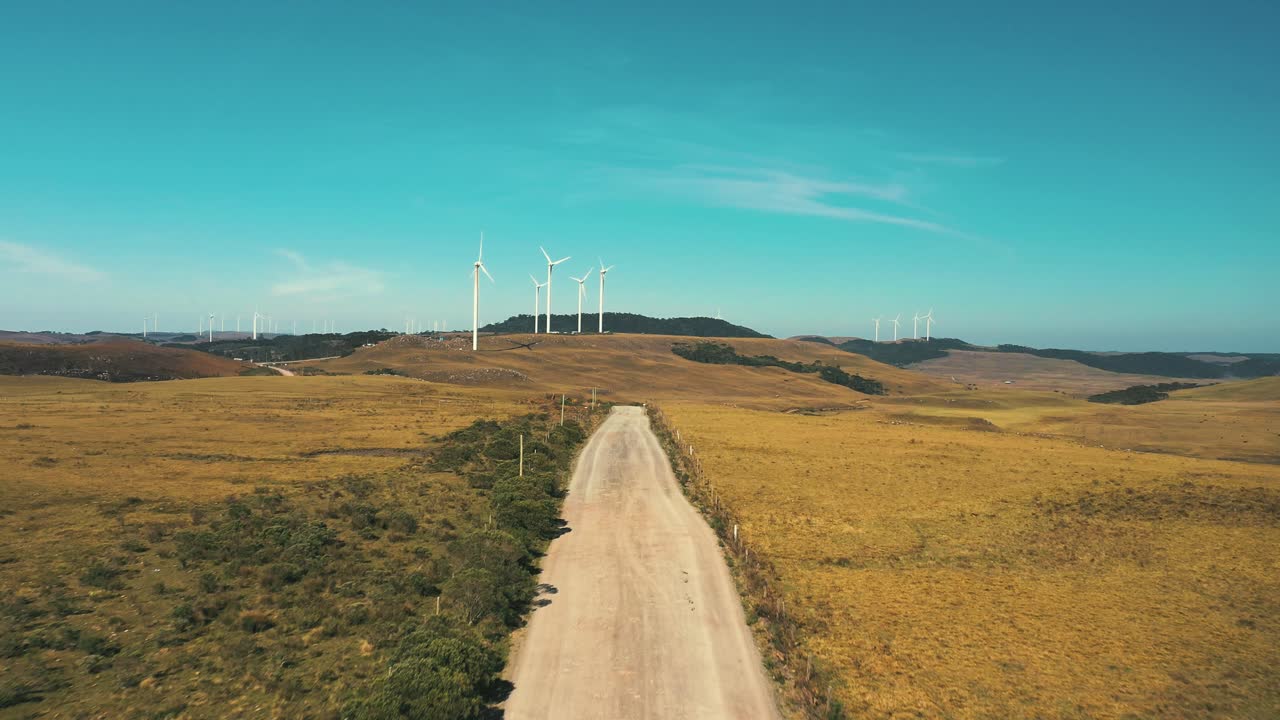 브라질 산타 카타리나에 위치한 풍력 터빈 발전기가 있는 비포장 도로의 드론 시네마틱 샷