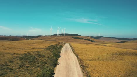 drone cinematic shot of dirt road with wind turbine generators located in santa catarina, brazil