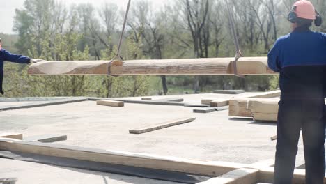 workers lifting large wooden beams for log house construction