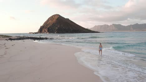 mujer joven en traje de baño caminando en olas en la playa, hawaii, cámara lenta