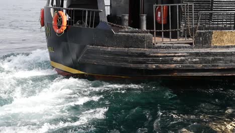 a close-up of a black boat in the water with white waves around it.