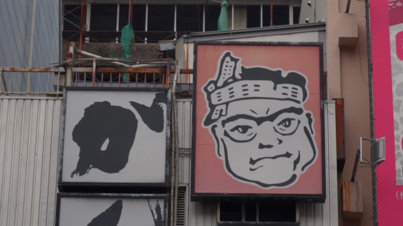 Close-up of Japanese Street Signs Featuring a Cartoon Character and Sushi Text