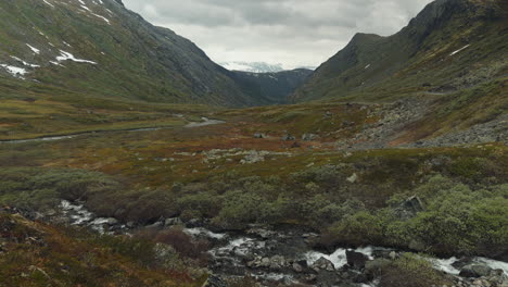 slow pan of a beautiful long valley with flowing stream over rocks in the foreground