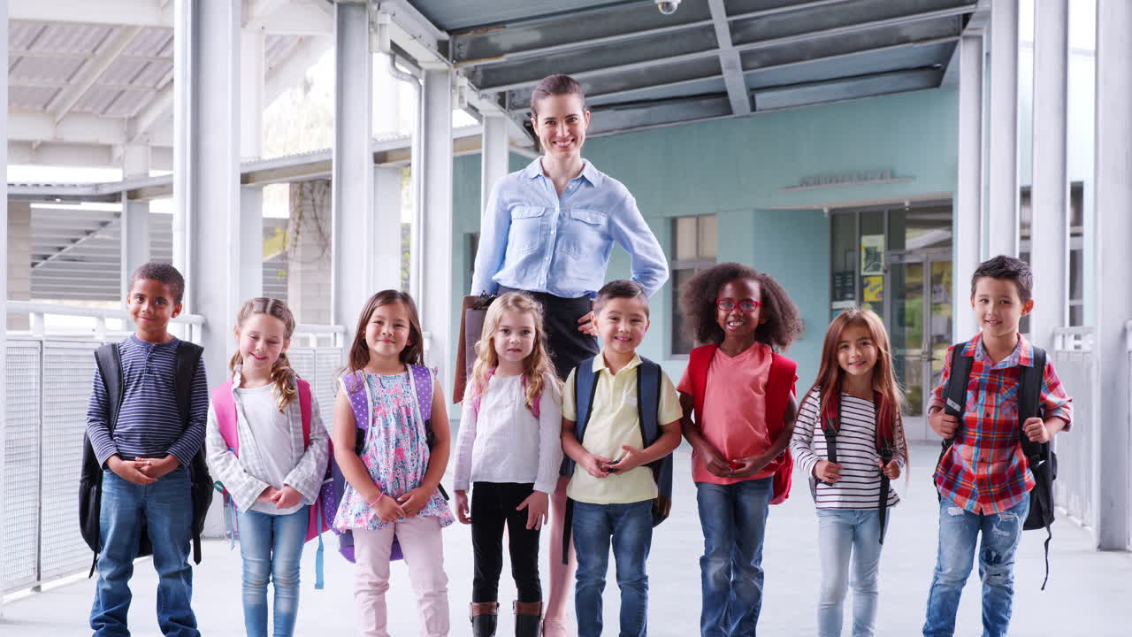 Grundschullehrerin und ihre Schüler im Schulflur.