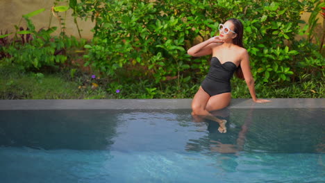 Attractive-Asian-Woman-in-Swimsuit-Sitting-on-Pool-Edge-on-Tropical-Destination