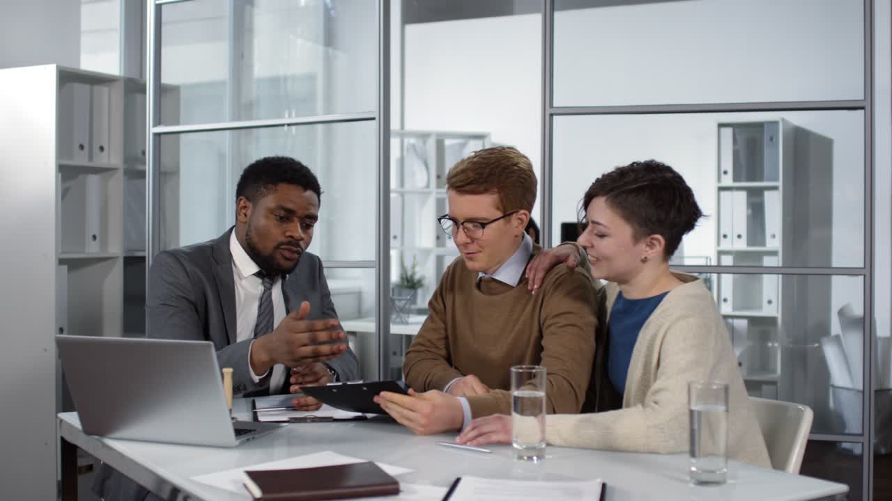 Couple Meeting With An Notary Looking At Computer In Office