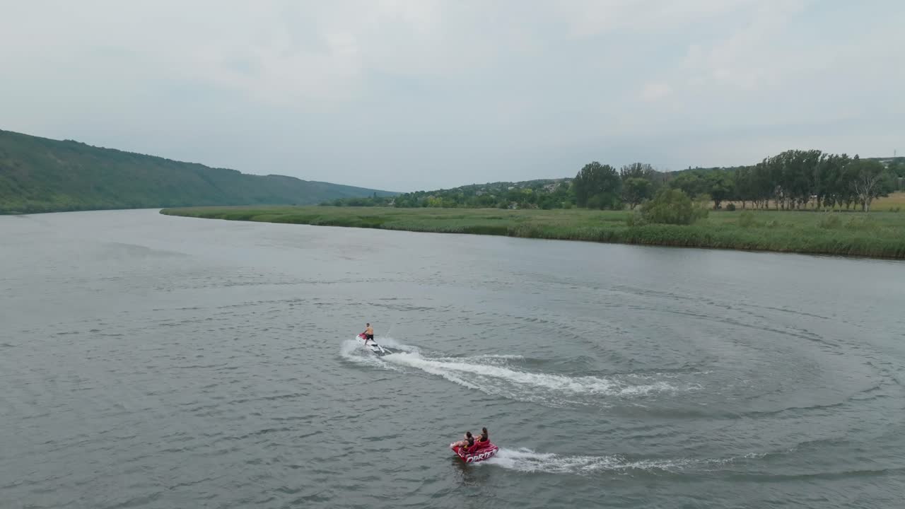 водный велосипед движется вдоль реки и тянет искателей острых ощущений вместе с ним