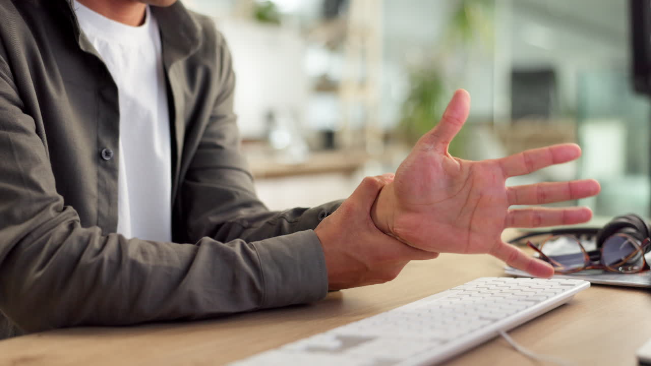 persona que trabaja en una computadora y experimenta dolor en la mano