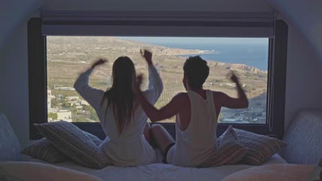 young fit millennial couple celebrate amazing hotel room view in coastal european greece