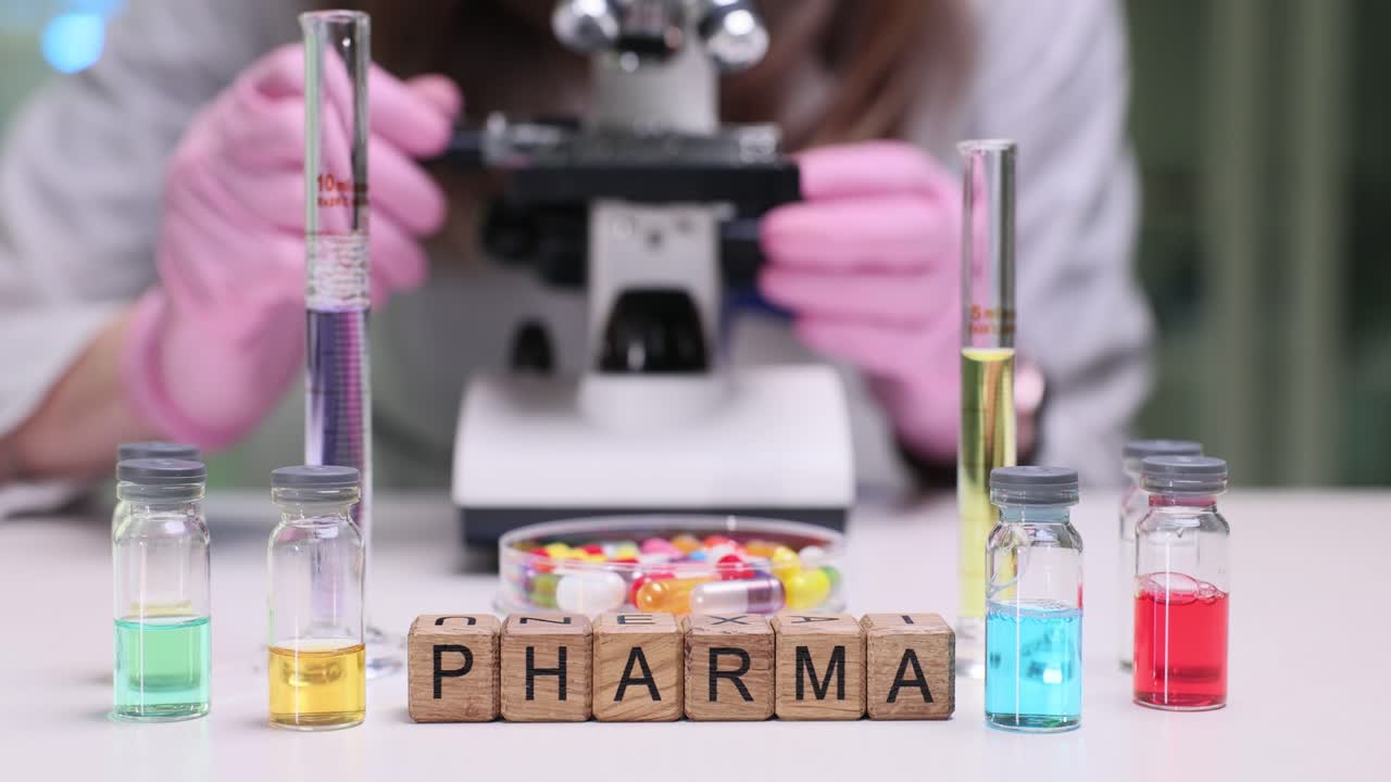 Cubi di legno compongono la parola 'pharma' su un luminoso tavolo da laboratorio, vicino a un farmacista