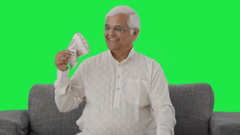 Happy-Indian-old-man-using-money-as-fan-Green-screen