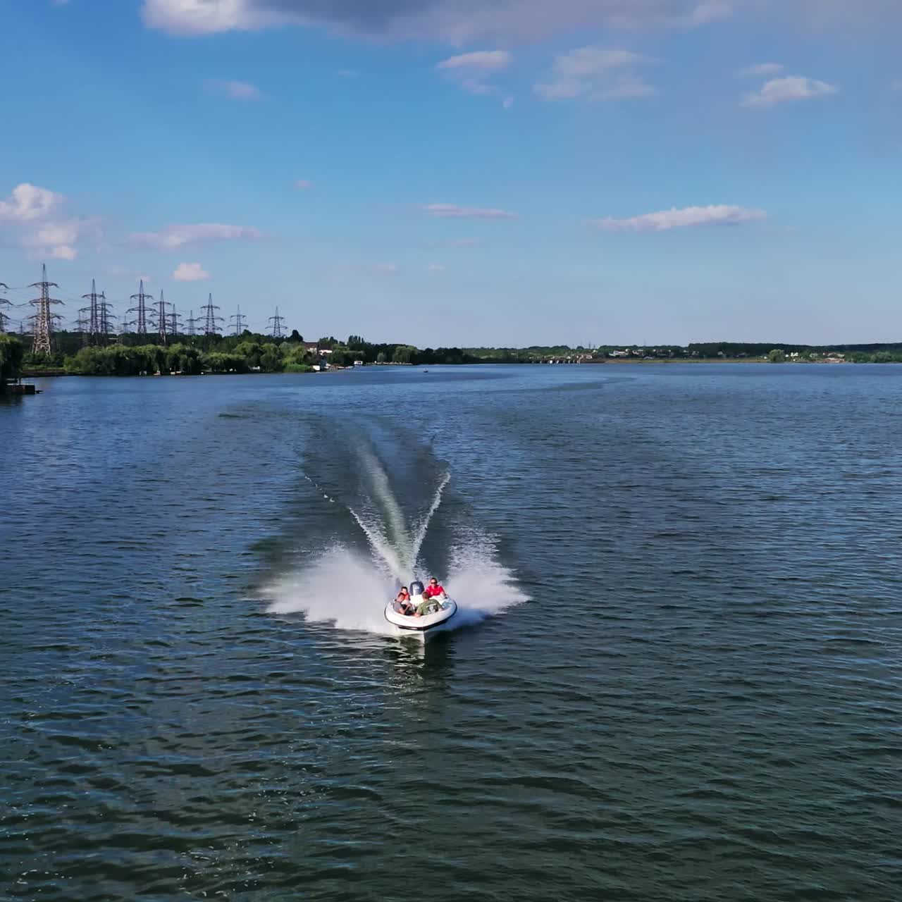 Boat sailing in the river. People travel in motorboat on the background of high voltage electric lines in summer. Aerial view.