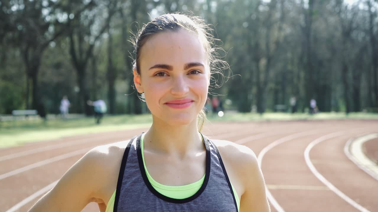 Young athletic woman in sportswear resting after jogging workout at track and field stadium