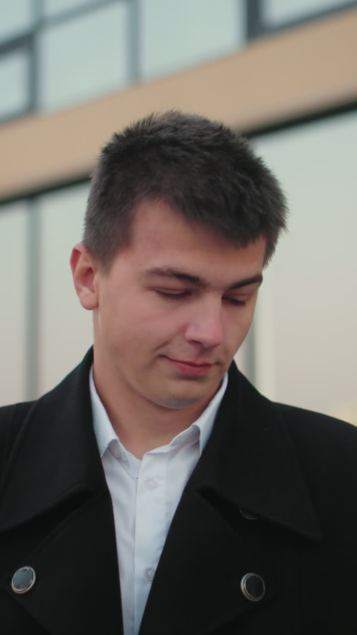 검은 코트를 입은 부동산 거장, 자신감 넘치는 모습으로 시간을 확인하고, 현대적인 유리 건물을 특징으로하는 배경, 전문적이고 성공적인 사업가, 도시 환경에 대한 자신감을 발산합니다.