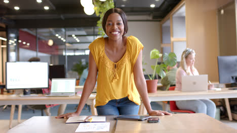 portrait of happy african american casual businesswoman standing in office smiling, slow motion