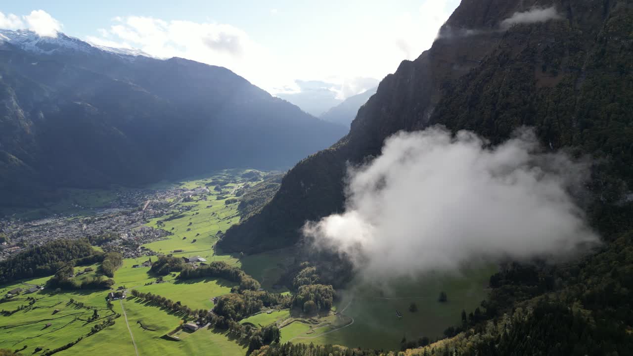 disparo de izquierda a derecha capturando una nube blanca flotando sobre el valle verde rodeado de altas cumbres montañosas