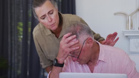 una pareja de ancianos caucásicos estresados con una computadora portátil calculando las finanzas juntos en casa