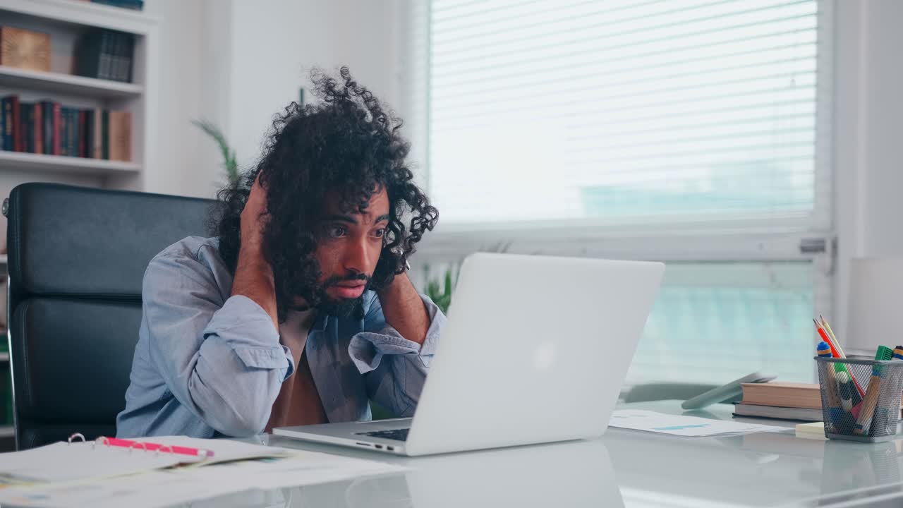 Frustrated arabian man clutches head when sees mistake or bad news in laptop
