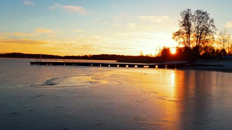 lapso de tiempo del muelle del embarcadero y la puesta de sol dorada en el invierno, el agua hace que el hielo delgado palpite y salte