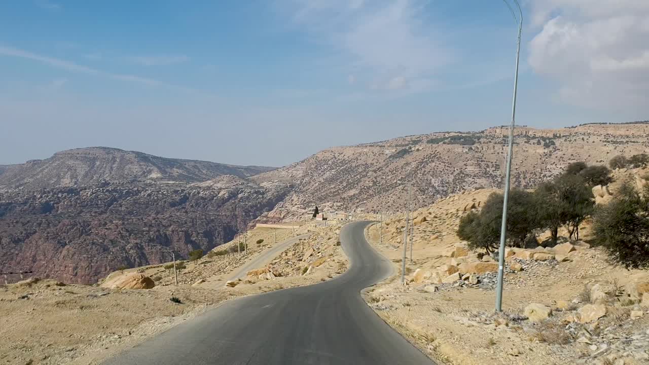 conduciendo por una panorámica carretera sinuosa en un remoto desierto a través de un entorno montañoso rocoso y escarpado en jordania, oriente medio