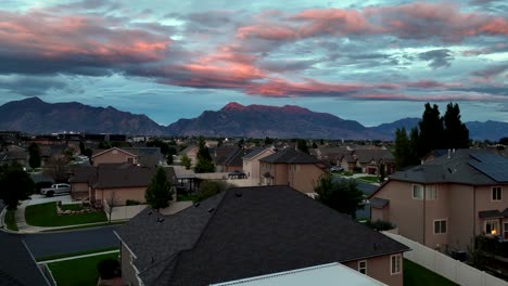 rising above a suburb to reveal the sunset reflecting off the clouds and mountain peaks