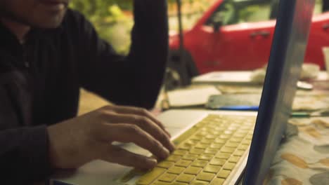 un tipo que trabaja en su computadora en el campo, oficinas móviles, trabajo remoto