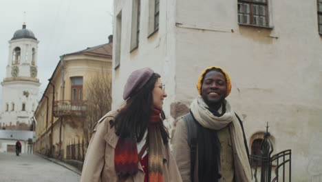 multiethnic tourist couple walking in town and discussing architecture