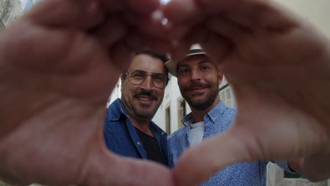 homosexual men standing and making heart with hands